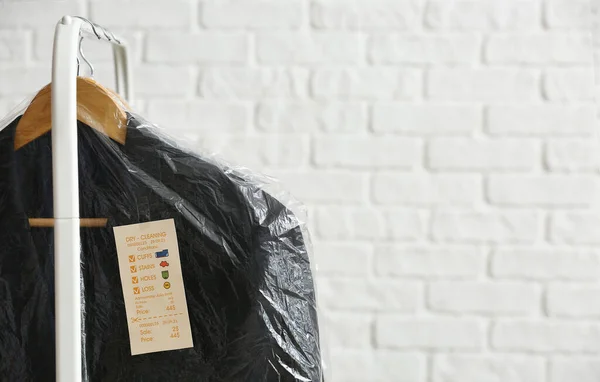 Scaffale Con Giacche Nere Pulite Sacchetti Plastica Sfondo Mattone Bianco — Foto Stock