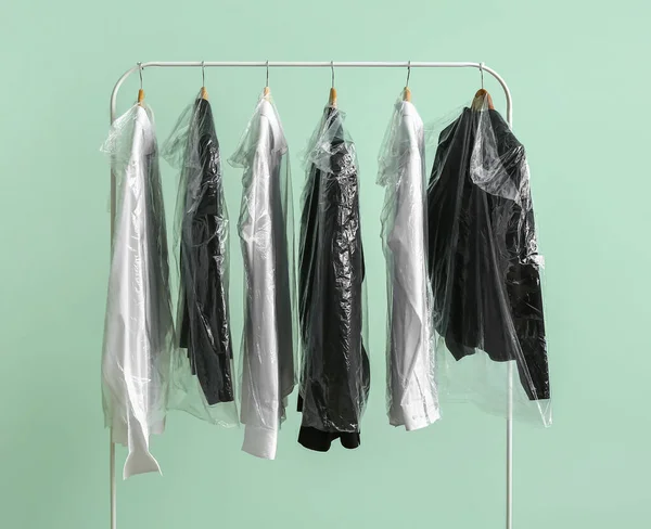 Rack Met Schone Jassen Shirts Plastic Zakken Groene Achtergrond — Stockfoto