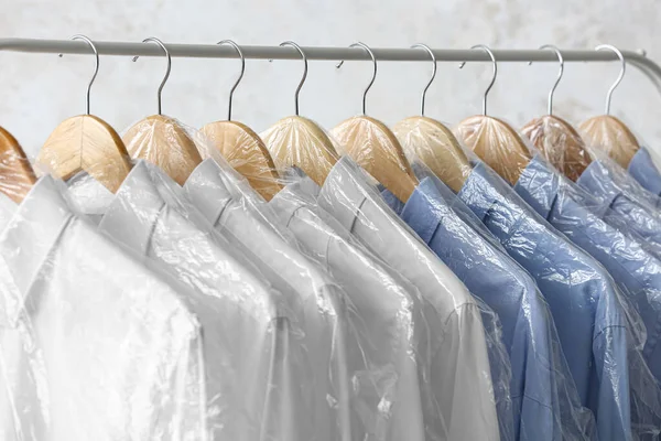 Rack Met Schone Witte Blauwe Shirts Plastic Zakken Lichte Achtergrond — Stockfoto