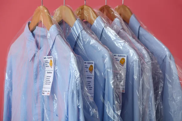 Scaffale Con Camicie Blu Pulite Sacchetti Plastica Sfondo Rosa Primo — Foto Stock