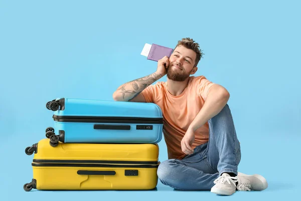 Glücklicher Junger Mann Mit Pass Und Koffer Auf Blauem Hintergrund — Stockfoto