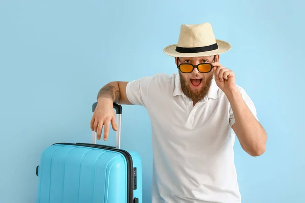 Glücklicher Junger Mann Mit Sonnenbrille Und Koffer Auf Blauem Hintergrund — Stockfoto