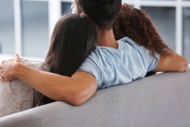 Erkek ve iki güzel kadın kanepede oturuyor. Poliyamory konsepti