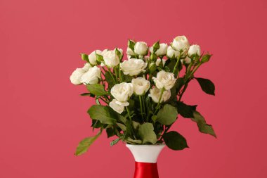 Kırmızı arka planda bir buket güzel gül olan vazo.