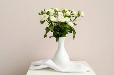 Vazo dolusu güzel güllerle aydınlık duvarın yanındaki masada.