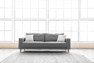 Büyük pencerenin yanında yastıklı gri kanepe