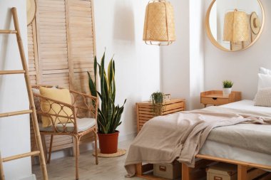 Hasır sandalye ve ev bitkisi yatak odasının iç tarafındaki ışıklı duvarın yanında.