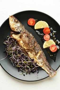 Hafif arka planda balık ve sebzeli lezzetli deniz otobüsleri tabağı.