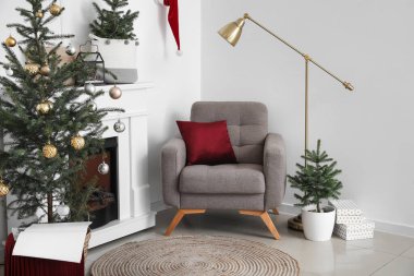 Oturma odasının içinde koltuk, lamba ve Noel ağaçları var.