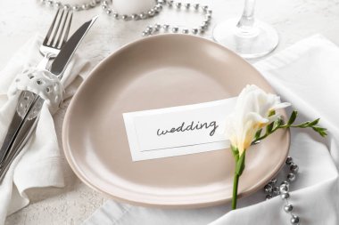 Güzel masa düzenleme, çiçekler ve beyaz arka planda düğün davetiyesi.