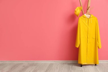 Sarı yağmurluk ve pembe duvarın yanında şapka