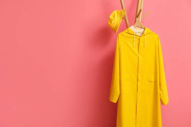 Sarı yağmurluk ve pembe duvarın yanında şapka