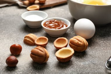 Gri arka planda haşlanmış konsantre sütle lezzetli ceviz şekilli kurabiyeler.