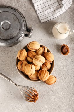 Gri arka planda kaynamış konsantre sütle ceviz şeklinde kurabiyeler.
