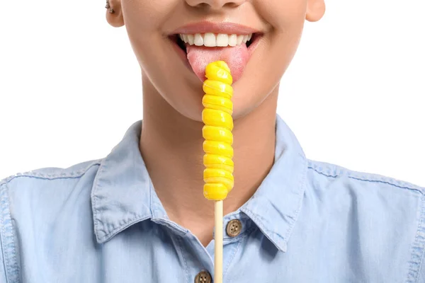 年轻女子在白色背景下吃甜黄色棒棒糖 — 图库照片