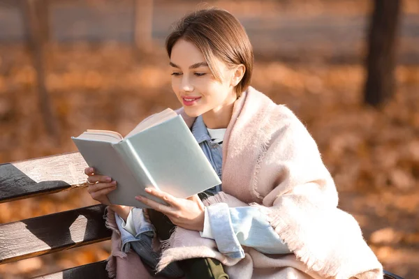 Sonbahar Parkındaki Ahşap Bankta Ekose Kitap Okuyan Genç Bir Kadın — Stok fotoğraf