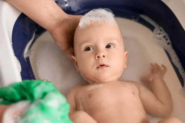 母親は赤ん坊の男の子を家で緑色のスポンジで洗い 閉じます — ストック写真