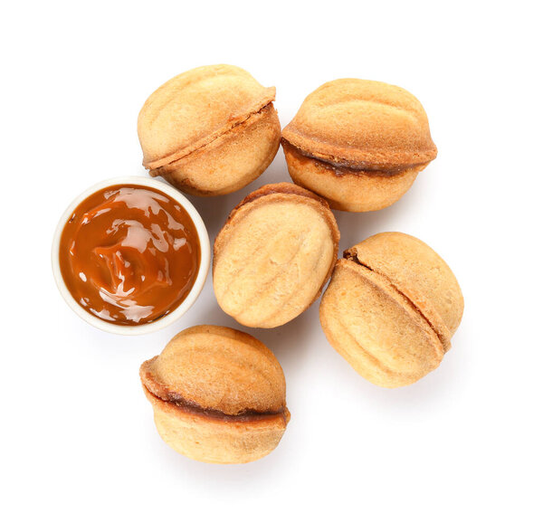 Tasty walnut shaped cookies with boiled condensed milk on white background