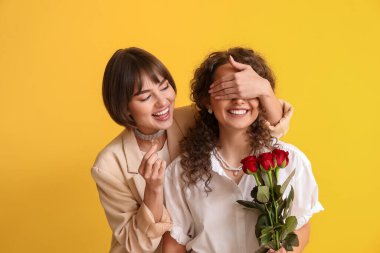 Genç lezbiyen kadın renkli arka planda kız arkadaşına evlenme teklif ediyor.