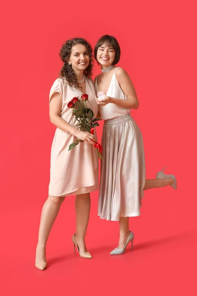 Jong Lesbisch Paar Met Verlovingsring Bloemen Kleur Achtergrond — Stockfoto