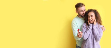 Genç adam sarı arka planda kız arkadaşına evlenme teklif ediyor.