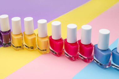 Renkli arka planda tırnak cilası şişeleri