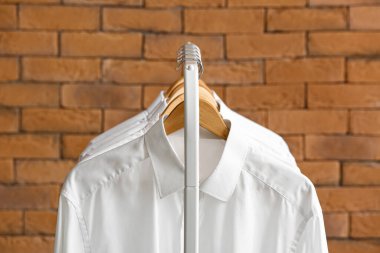 Tuğla duvarın yanında temiz gömlekli raflar