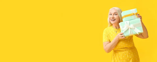Uśmiechnięta Dojrzała Kobieta Prezentami Żółtym Tle Miejscem Tekst Międzynarodowy Dzień — Zdjęcie stockowe