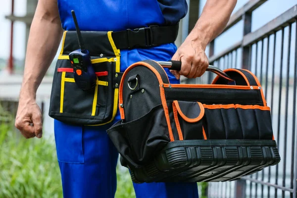 Alet çantası ve şantiyesi olan erkek işçi.