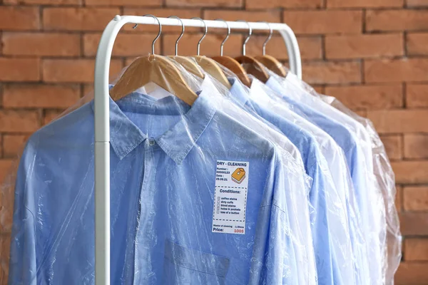 Rack Met Schone Shirts Plastic Zakken Buurt Van Bakstenen Muur — Stockfoto
