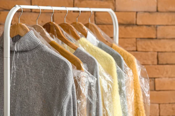 Rack Met Schone Truien Plastic Zakken Buurt Van Bakstenen Muur — Stockfoto