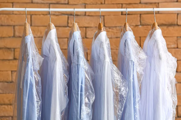 Rack Met Schone Shirts Plastic Zakken Buurt Van Bakstenen Muur — Stockfoto