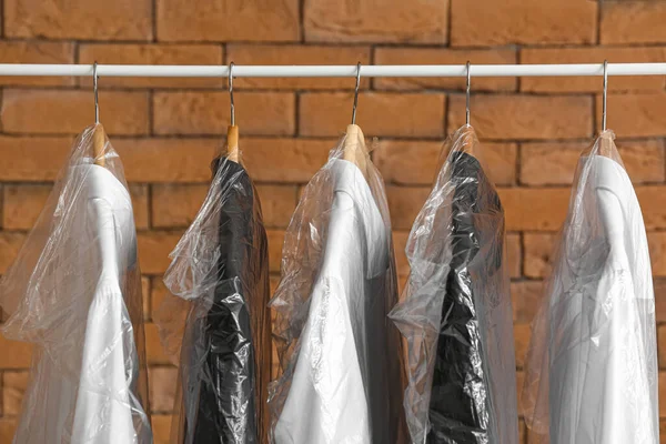 Σχάρα Καθαρά Πουκάμισα Πλαστικές Σακούλες Κοντά Τοίχο Από Τούβλα — Φωτογραφία Αρχείου