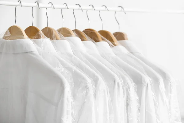 Rack Met Schone Shirts Plastic Zakken Buurt Van Lichte Muur — Stockfoto