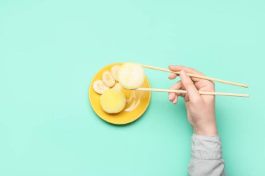 Kadın nefis mochi yiyor, yemek çubukları da arka planda.