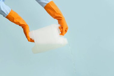 Adam plastik kutudan renk arkaplanına sıvı döküyor