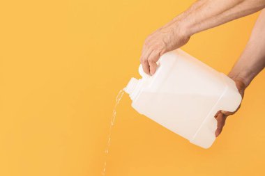 Adam plastik kutudan renk arkaplanına sıvı döküyor