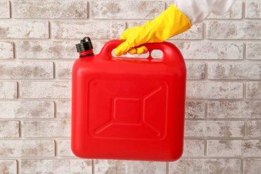 Lastik eldivenli bir erkek, tuğla duvarın yanında bir kutu tutuyor.