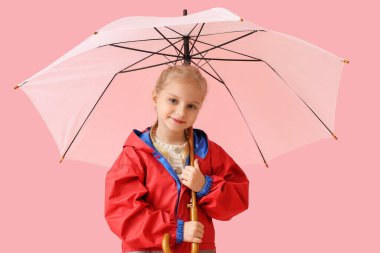 Şık yağmurluklu ve arka planda şemsiyesi olan küçük bir kız.