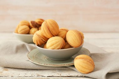 Ahşap masada kaynamış konsantre sütle ceviz şeklinde kurabiyeler.