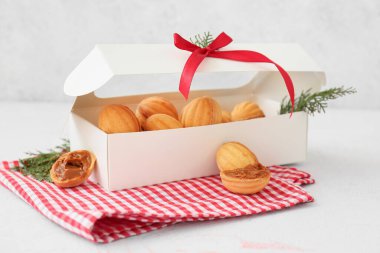 Lezzetli ceviz şeklinde kurabiyelerle dolu bir kutu haşlanmış süt ve hafif arka planda thuja dalları.