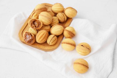 Ahşap ahşap ahşap tahta ceviz şekilli kurabiyeler ve hafif arka planda kaynamış konsantre süt.