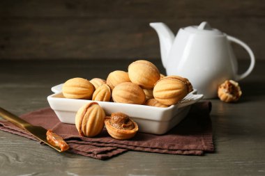 Koyu ahşap zemin üzerinde kaynamış yoğunlaştırılmış sütle lezzetli ceviz şeklinde kurabiyeler pişirmek.