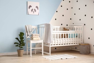 Odanın içinde sandalyede, karyolada ve çiçeklerde renkli duvarların yanında süveterler var.