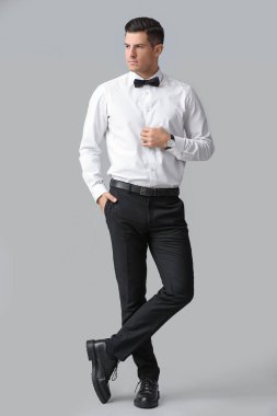 Modaya uygun bir beyefendi gri arka plana bakıyor.