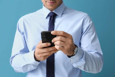 Resmi kıyafetli yakışıklı arka planda cep telefonu kullanıyor, yakın plan.