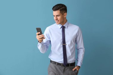 Renkli arka planda cep telefonu kullanan resmi kıyafetli yakışıklı bir adam.