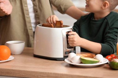 Annesiyle küçük bir çocuk mutfakta lezzetli tost yapıyor, yakın plan.