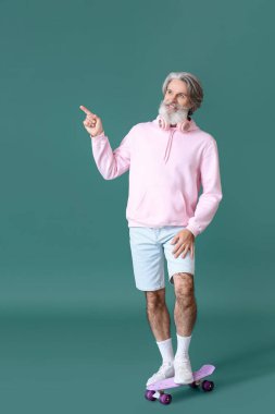 Kaykaylı son sınıf öğrencisi yeşil arka planda bir şeye bakıyor.