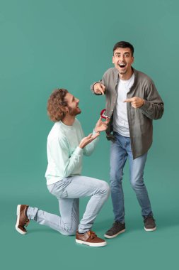 Genç gay yeşil arka planda erkek arkadaşına evlenme teklif ediyor.